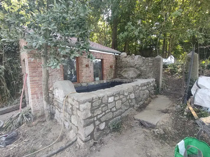 Mur en pierre du pays remonté et bassin en cours d'étanchéité