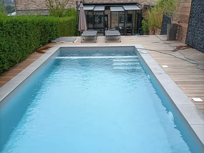 Piscine terminée à Jupille, margelles claires et terrasse en bois exotique