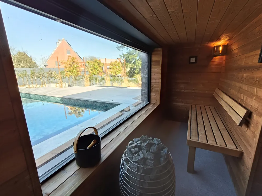 Sauna en thermobois à vitrage panoramique ouvert sur la piscine, réalisé par Sebonard à Liège